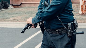 Policial com arma em punho - Pexels