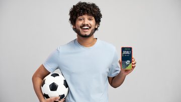 Pessoa mostrando tela de celular segurando bola de futebol - Freepik