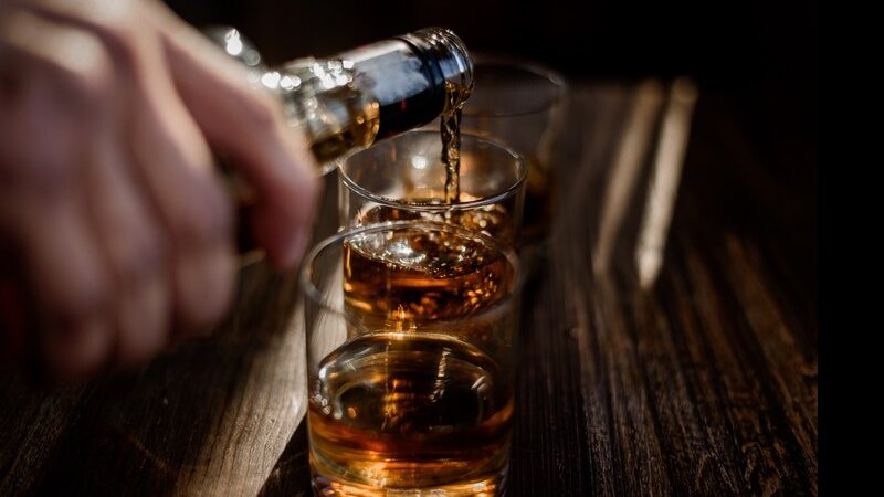 Enchendo copo de whisky - Freepik