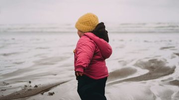 Criança agasalhada na praia