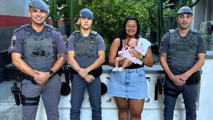 Mãe com a bebê Lívia no colo junto com os policiais