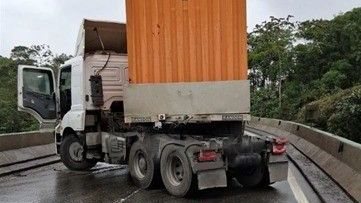 Carreta para transversalmente na pista, após a colisão com a barreira