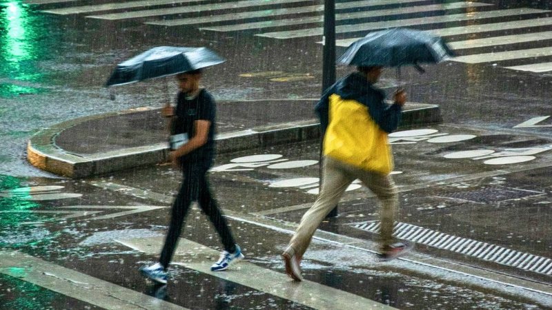 Pessoas atravessando a rua com guarda-chuva