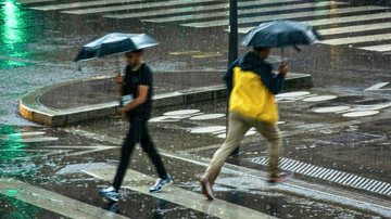 Pessoas atravessando a rua com guarda-chuva