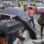 Esta imagem mostra pessoas abrigadas com guarda-chuvas numa paragem de autocarro durante um dia chuvoso em Santos