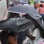 Esta imagem mostra pessoas abrigadas com guarda-chuvas numa paragem de autocarro durante um dia chuvoso em Santos