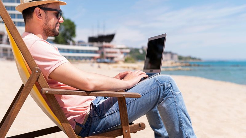 Homem na praia, com notebook