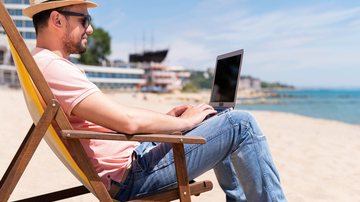 Homem na praia, com notebook
