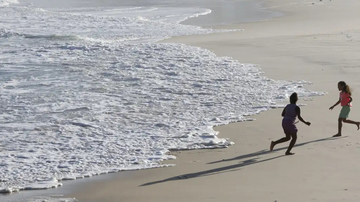Duas crianças correndo na beira do mar