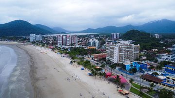 Vista da Praia de Bertioga em dia ensolarado, com faixa de areia extensa e mar calmo