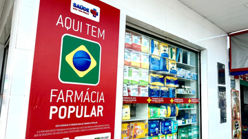 Fachada de farmácia com banner do programa Farmácia Popula e produtos expostos