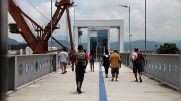 Pedestres atravessando passarela para chegar a balsa Santos-Guarujá