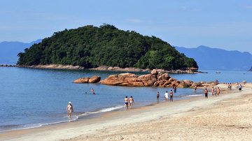 Pessoa usa máscara de mergulho e nada no mar, mantendo a cabeça fora da água e fazendo sinal positivo com o polegar