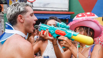 Mulher espirrando liquido na boca de homem com arma de brinquedo