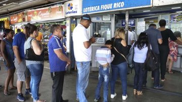 pessoas na fila de casa lotérica para realizar aposta