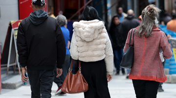 Pessoas andando na rua com casacos de frio