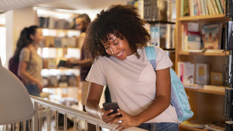 Estudante olhando aplicativo em biblioteca
