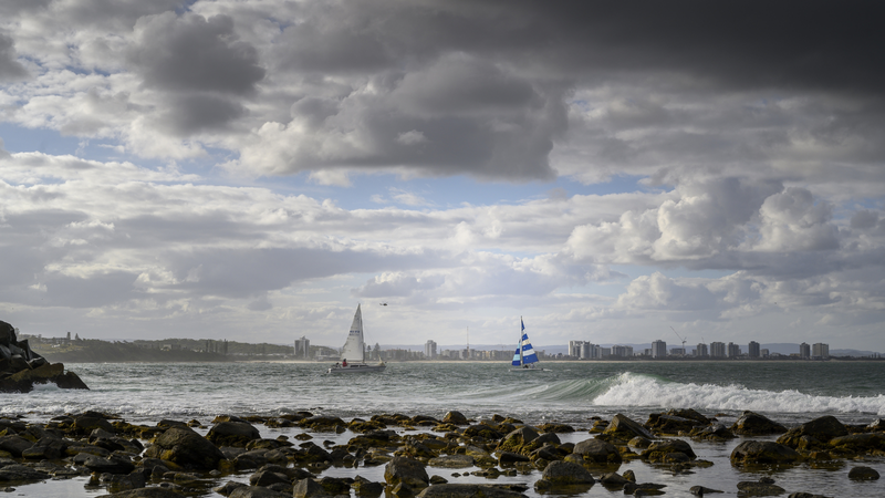 Céu com nuvens e barcos ao fundo em praia