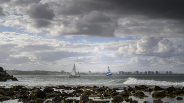 Céu com nuvens e barcos ao fundo em praia