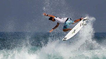Pessoa em uma prancha de surfe fazendo uma manobra em onda