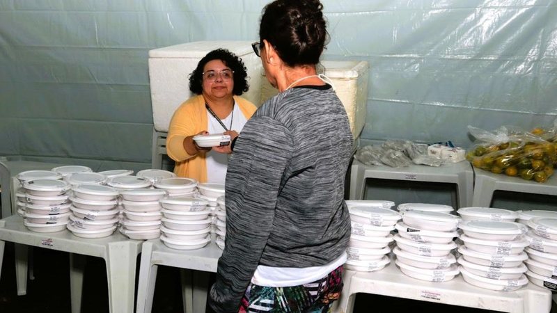 Mulher entrega marmita em mutirão de Santos