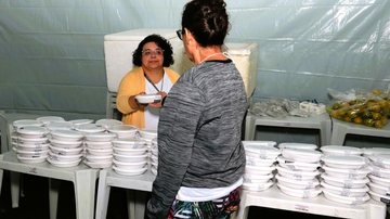 Mulher entrega marmita em mutirão de Santos