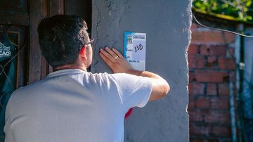 Imagem de um homem de costas com a mão em um muro