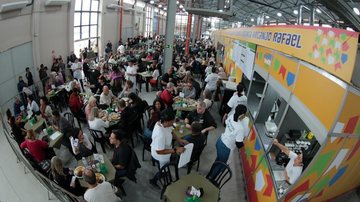Pessoas reunidas no evento, dentro do armazém