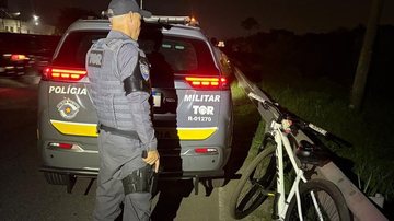 A imagem mostra a apreensão de uma bicicleta e um agente do Tático Ostensivo Rodoviário (TOR) de costas