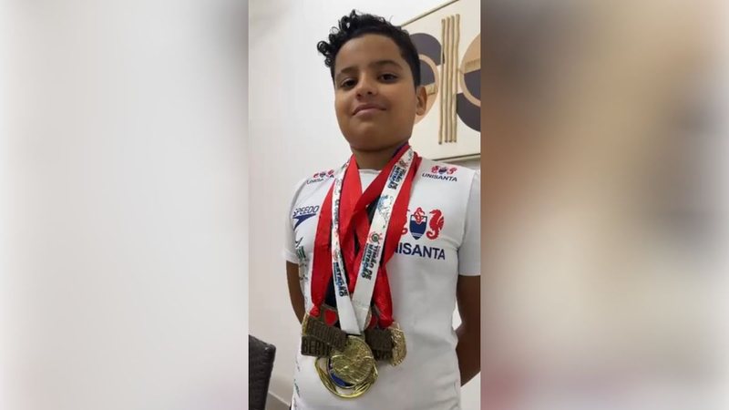 menino mostra as medalhas conquistadas