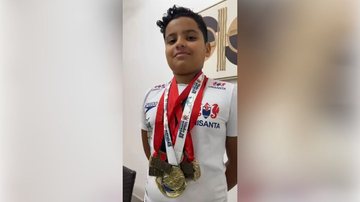 menino mostra as medalhas conquistadas