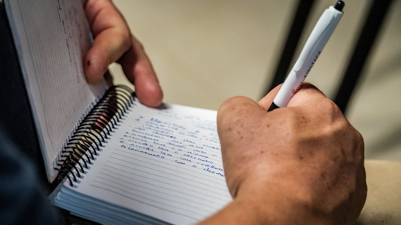 Imagem de uma pessoa escrevendo em um caderno