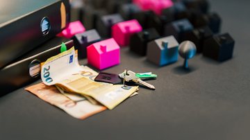 Notas de dinheiro, uma chave e miniaturas de casas