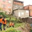 Imagem de casas em morro de Santos, e agentes da Defesa Civil na parte de baixo da imagem