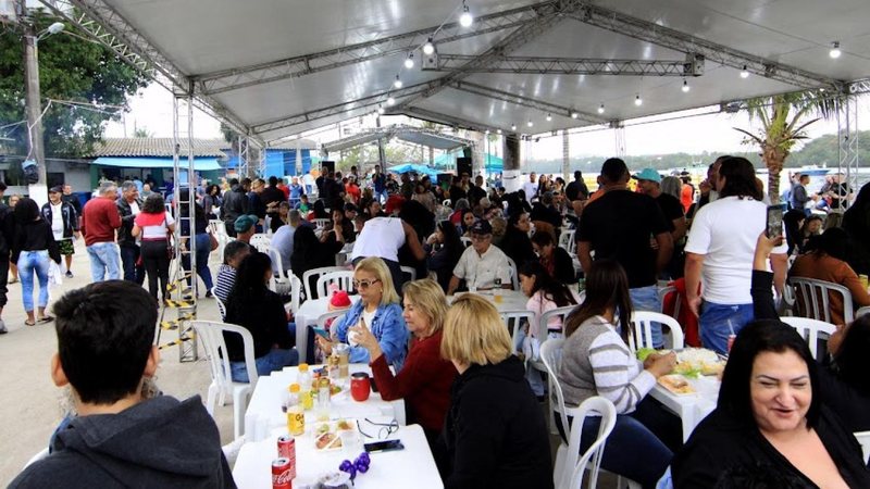 Imagem de várias pessoas sentadas em cadeiras, abaixo de uma tenda, no evento na Ilha Diana