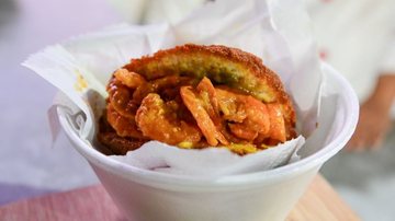 A imagem mostra um acarajé, um famoso bolinho da culinária baiana feito de massa de feijão-fradinho frito em azeite de dendê