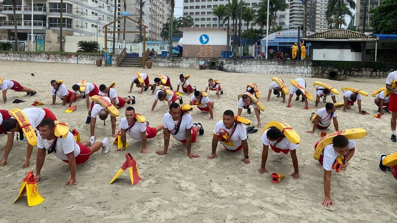 Imagem de diversos guardas-vidas fazendo exercícios na areia da praia