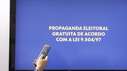 Foto de Tv ligada com os dizeres "propaganda eleitoral gratuita de acordo com a lei 9.504/97"