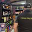 A imagem mostra uma operação de fiscalização numa adega ou loja de conveniência, com agentes públicos a vistoriarem o estabelecimento