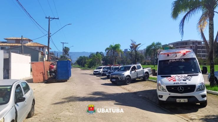 Imagem de uma rua de Ubatuba com viaturas de forças de segurança do lado direito
