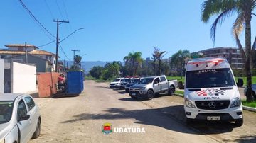 Imagem de uma rua de Ubatuba com viaturas de forças de segurança do lado direito