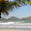 Praia do Perequê-Açú, em Ubatuba, com coqueiro em primeiro plano, ondas no mar e montanhas