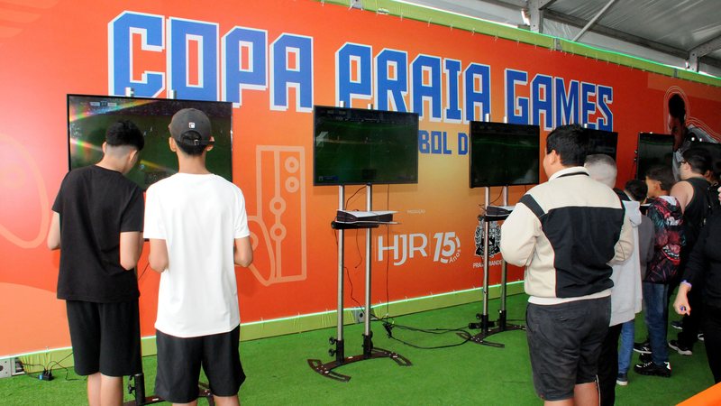 Foto de crianças jogando video game em pé, de costas para a imagem
