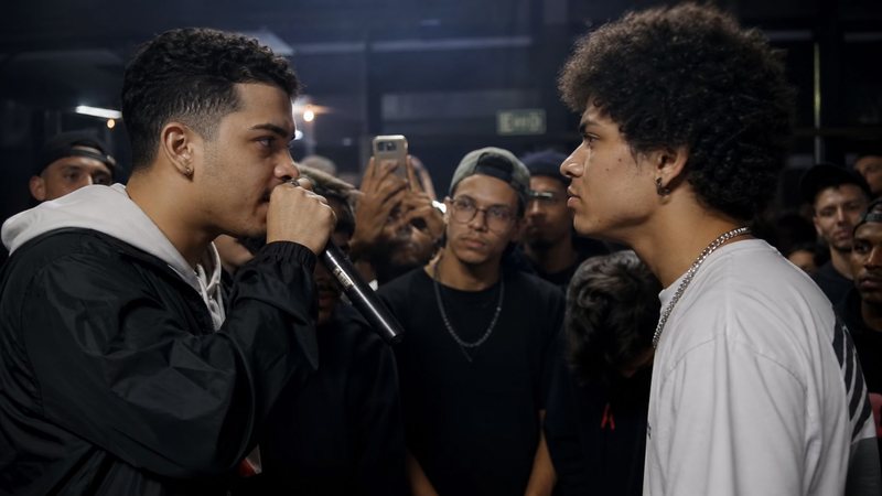 Dois homens jovens frente a frente em batalha de rima