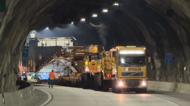 Imagem de um caminhão transportando uma carga muito grande e pesada em um túnel