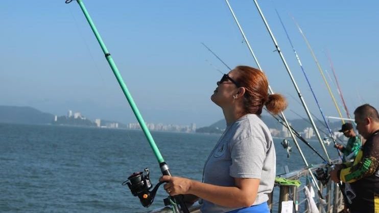 Foto de mulher pescando no Deck do Pescador, em Santos