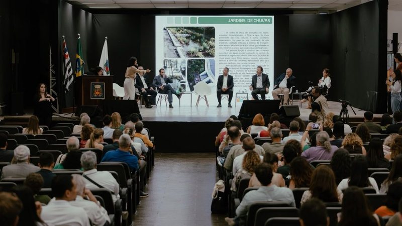 Pessoas reunidas em uma sala com um grande painel
