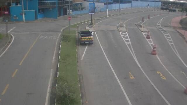 Área de espera para a travessia entre São Sebastião e Ilhabela, com faixas de acesso demarcadas, cones de sinalização e veículos aguardando