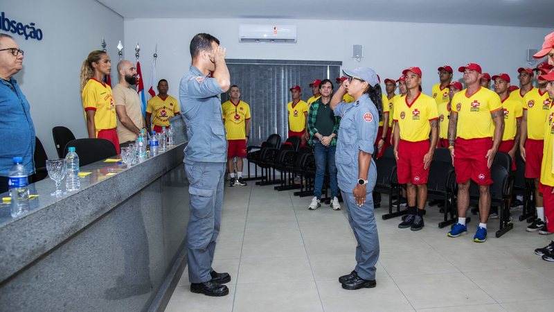 Imagem de diversos guarda-vidas fazendo posição de sentido para um superior