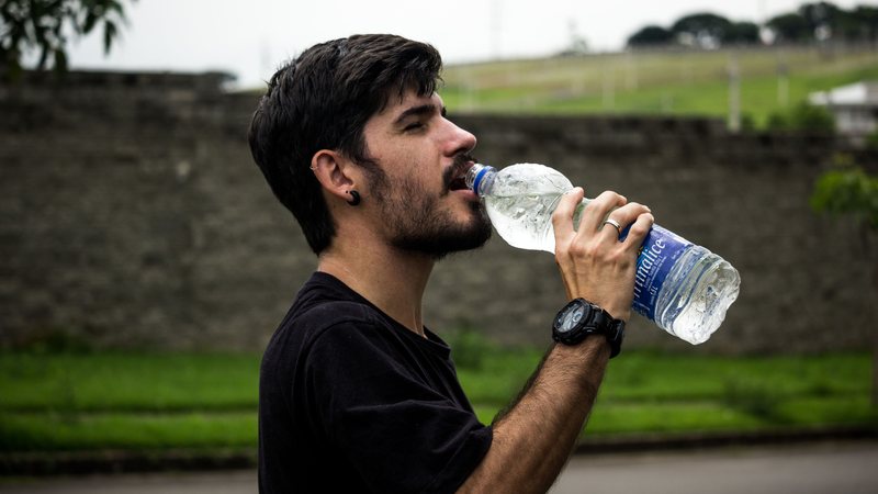 Homem bebe água durante um dia de calor intenso